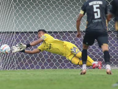 Kiper Dewa United FC, M Natshir Fadhil Mahbuby berusaha menghalau bola tendangan pemain Arema FC pada laga pekan pertama BRI Liga 1 2023/2024 antara Dewa United melawan Arema FC di Stadion Indomilk, Tangerang, Minggu (2/7/2023). (Bola.com/Bagaskara Lazuardi)
