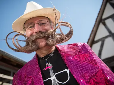 Salah satu peserta memperlihatkan janggut miliknya yang dibentuk menyerupai Menara Eiffel (kanan) sebelum mengikuti kompetisi janggut dan kumis di Ecomusee d'Alsace, Ungersheim, Prancis, 30 Maret 2017. (AFP PHOTO/SEBASTIEN BOZON)