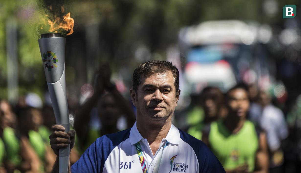 Pevoli legendaris Indonesia, Pascal Wilmar, berlari membawa obor Asian Games XVIII saat pawai di Denpasar, Bali, Selasa (24/7/2018). Sebanyak 53 kota di Indonesia akan dilalui oleh obor Asian Games. (Bola.com/Vitalis Yogi Trisna)