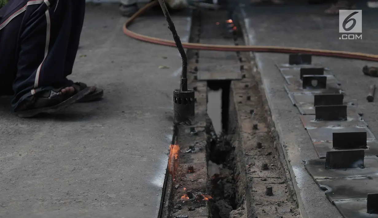Para pekerja memperbaiki aspal di flyover Kemayoran yang mengalami kerenggangan, Jakarta, Sabtu (5/1). Hal itu disebabkan rusaknya sambungan celah sambungan alias expansion joint. (Merdeka.com/Imam Buhori)