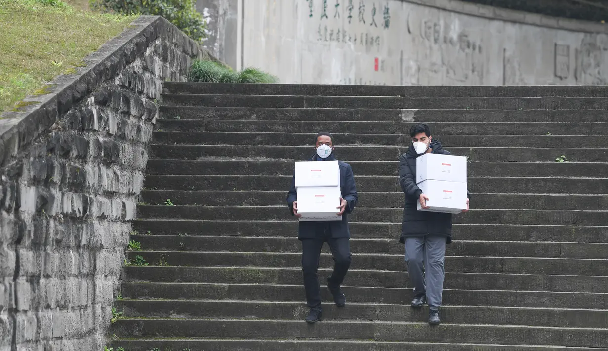 Iroegbu Paul Ikechukwu dari Nigeria dan Jimmy dari Pakistan membawa kotak berisi masker di Universitas Chongqing di Chongqing, China, 18 Februari 2020. Sejumlah pelajar asing di Chongqing ambil bagian dalam kampanye pengendalian epidemi dengan terlibat dalam pekerjaan sukarela (Xinhua/Wang Quanchao)