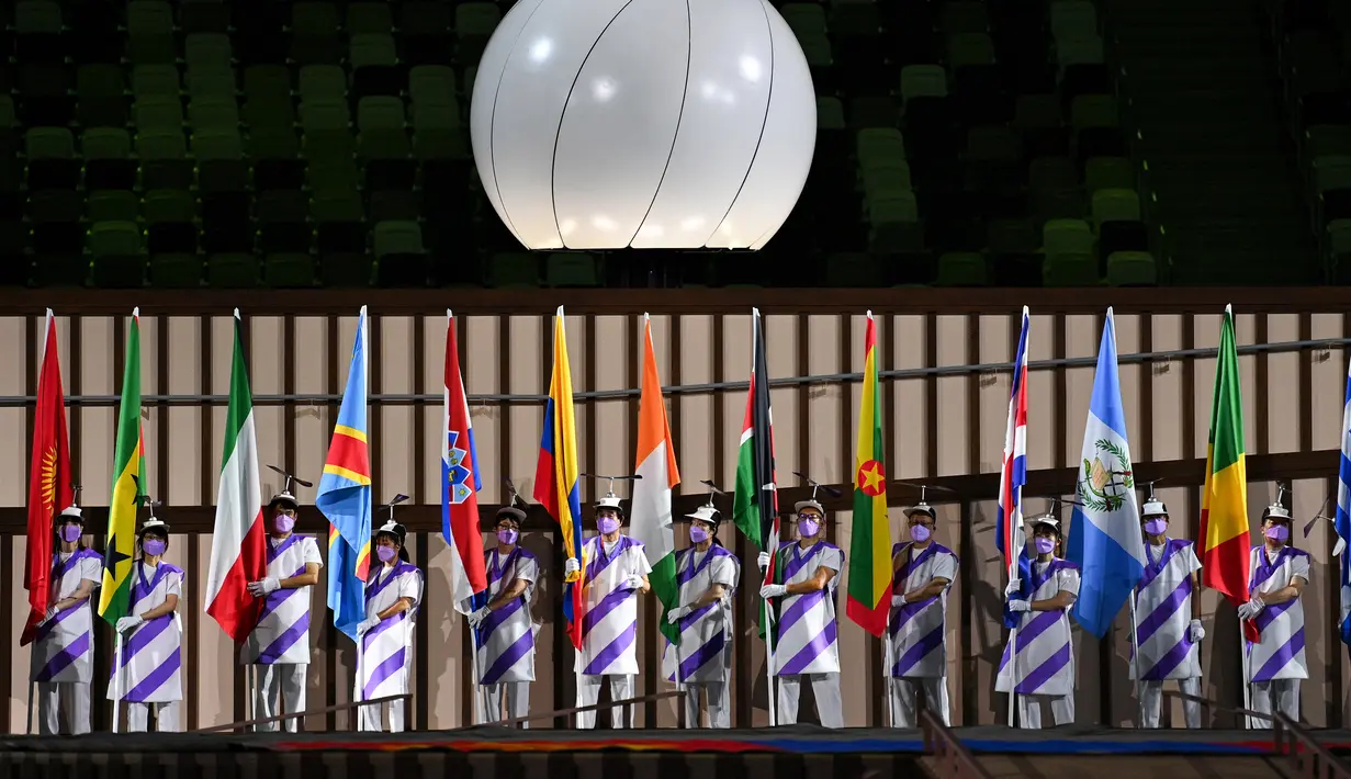 Relawan memegang bendera delegasi saat upacara pembukaan Paralimpiade Tokyo 2020 di Olympic Stadium, Tokyo, Selasa (24/8/2021) Bendera Afghanistan dikibarkan dalam defile tanpa kehadiran satu pun atletnya menyusul kondisi negaranya pasca dikuasai oleh Taliban. (Philip FONG / AFP)