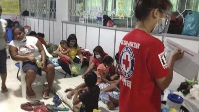 Keluarga tinggal di pusat evakuasi sementara di provinsi Catanduanes, Filipina timur, Minggu (1/11/2020). Badan cuaca Filipina mengatakan Topan Goni diperkirakan menghantam ujung tenggara Pulau Luzon pada Minggu (1/11/2020) dengan kecepatan angin 205 kilometer per jam. (Philippine Red Cross via AP)