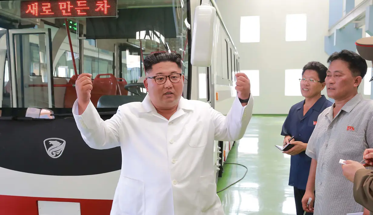 Pemimpin Korea Utara Kim Jong-Un berbincang selama kunjungan ke pabrik bus di Pyongyang, Korea Utara, (4/8). Dalam kunjungannya Kim Jong-un juga melihat langsung proses produksi bus. (AFP Photo/KCNA)