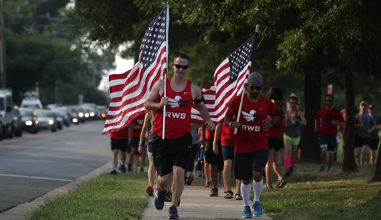 Sejumlah warga yang tergabung dalam kelompok veteran berlari sambil membawa bendera Amerika Serikat untuk menunjukan solidaritas terkait penembakan di Virginia, AS (14/6). (Alex Wong/Getty Images/AFP)