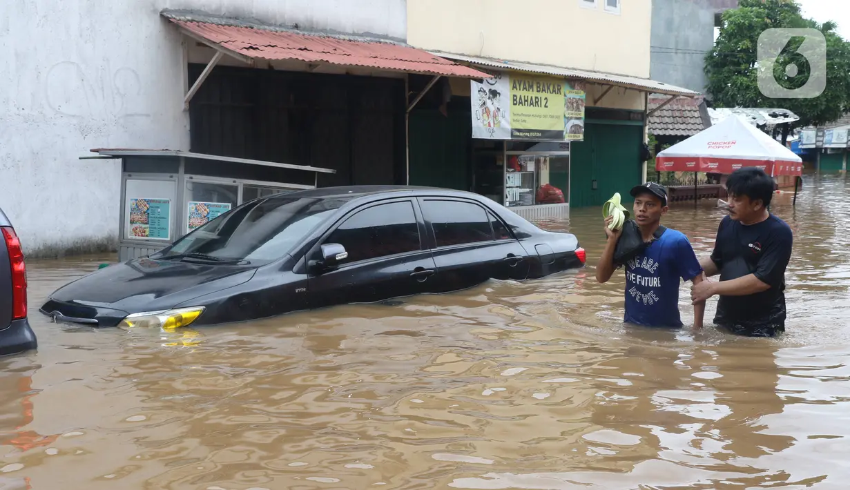 Warga melintasi banjir di perumahan Ciledug Indah, Tangerang, Rabu (1/1/2020). Banjir setinggi dada orang dewasa terjadi akibat meluapnya kali angke. (Liputan6.com/Angga Yuniar)