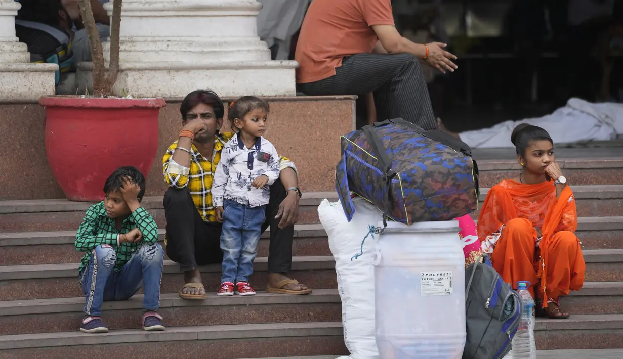 Sebuah keluarga menunggu moda transportasi lain selama pemogokan yang diserukan oleh operator transportasi swasta  di New Delhi, India, 18 April 2022. Berbagai serikat pekerja bajaj dan taksi di ibu kota mogok menuntut subsidi untuk gas alam terkompresi. (AP Photo/Manish Swarup)