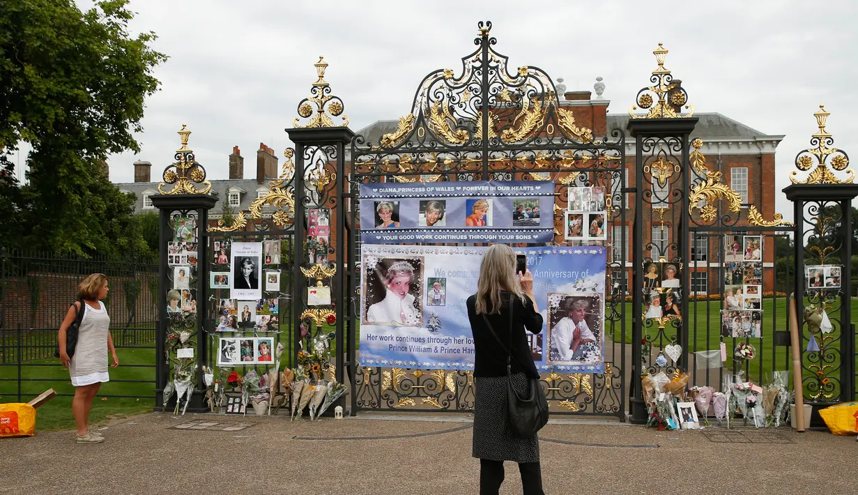 Seorang wanita mengambil gambar memorabilia Putri Diana di luar Istana Kensington, London, Selasa (29/8). Pernak-pernik serta bunga didedikasikan khusus untuk sang putri yang meninggal akibat kecelakaan mobil pada 31 Agustus 1997 (AP Photo/Alastair Grant)