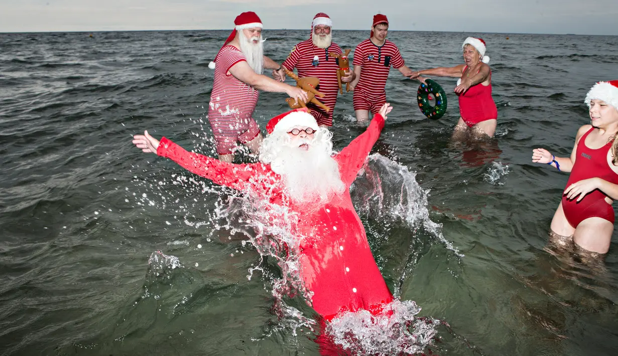 Sinterklas dari penjuru dunia menikmati bermain air laut Klampenborg di luar Kopenhagen, Denmark, Selasa (25/7). Lima bulan menjelang natal, ratusan Sinterklas berkumpul dalam Kongres Dunia Sinterklas yang ke 60. (Tobias Nicolai / Ritzau Foto via AP)