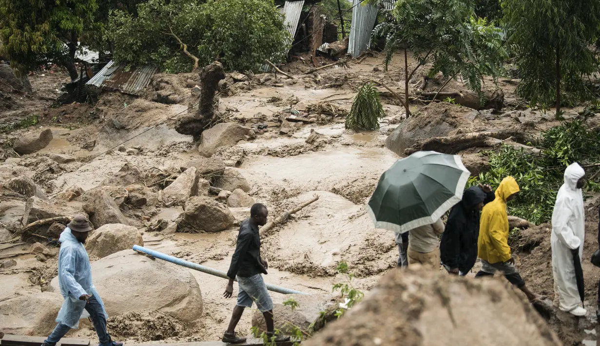 Orang-orang menyeberangi sungai yang mengamuk di Blantyre, Malawi, Senin, 13 Maret 2023. Topan Freddy yang tak henti-hentinya yang saat ini menghantam Afrika bagian selatan telah menewaskan sedikitnya 56 orang di Malawi dan Mozambik sejak melanda benua itu untuk kedua kalinya pada Sabtu malam, otoritas di kedua negara telah mengkonfirmasi. (AP Photo/Thoko Chikondi)