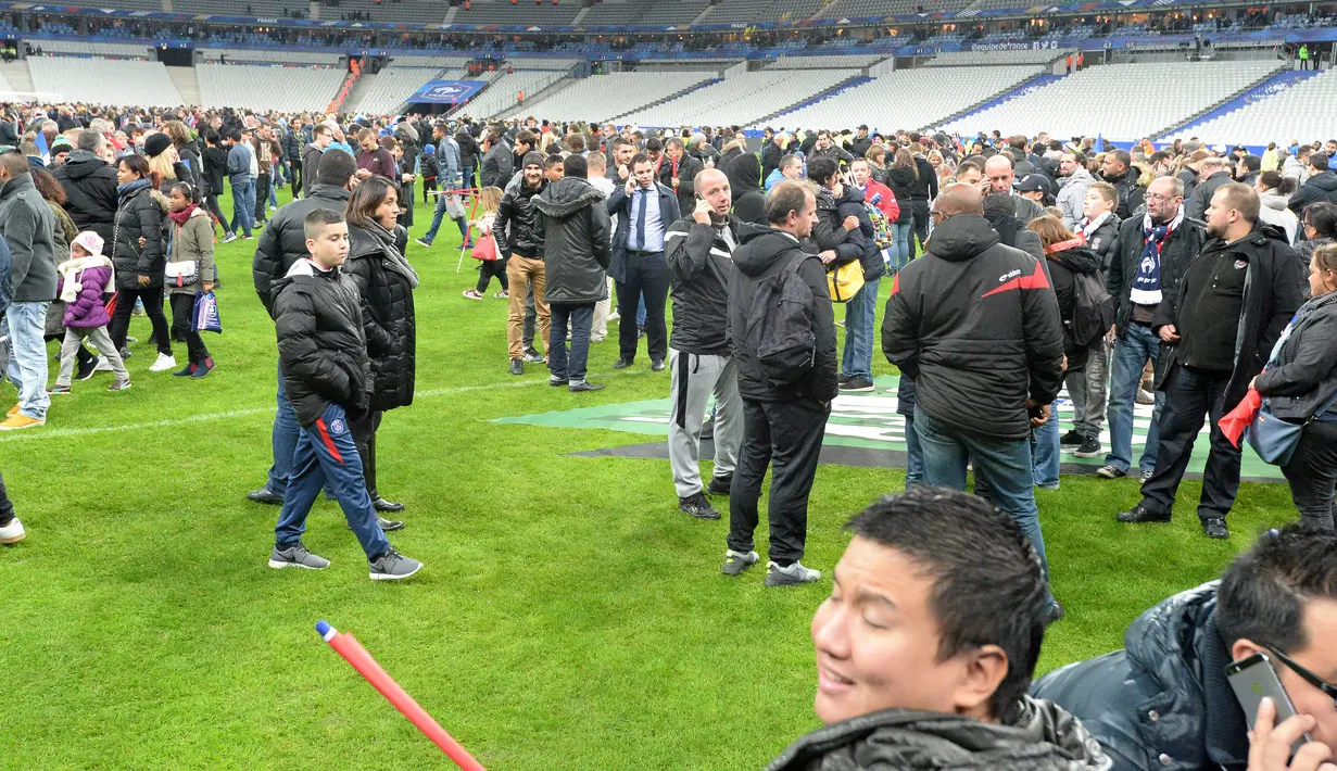 Ribuan Penonton berhamburan di lapangan stadion Stade de France saat menyaksikan pertandingan antara Prancis melawan Jerman di Saint-Denis, Paris, (13/11). Serangan bom terjadi di dekat stadion Stade de France Prancis. (AFP PHOTO/MIGUEL MEDINA)