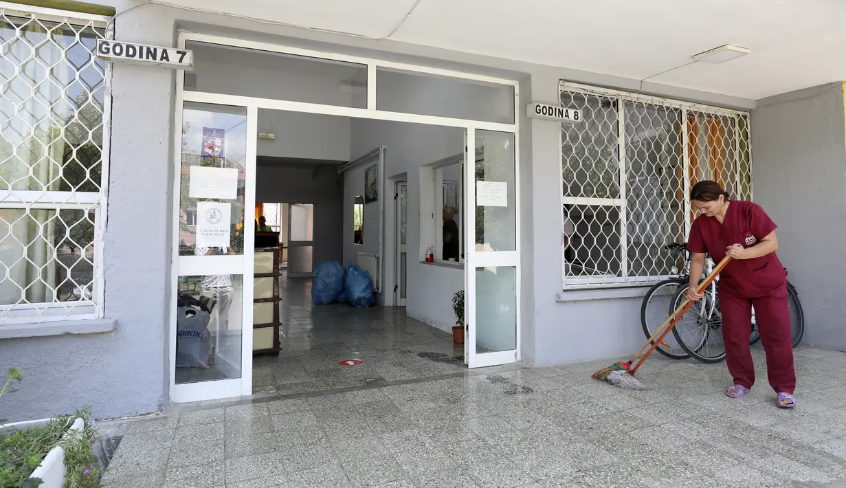 Seorang wanita mengepel pintu masuk kampus mahasiswa yang akan menampung warga Afghanistan, di Tirana, Albania, Rabu (18/8/2021).  Albania sedang mempersiapkan kedatangan warga Afganistan yang bekerja dengan pasukan penjaga perdamaian Barat yang terancam Taliban. (AP Photo/Franc Zhurda)
