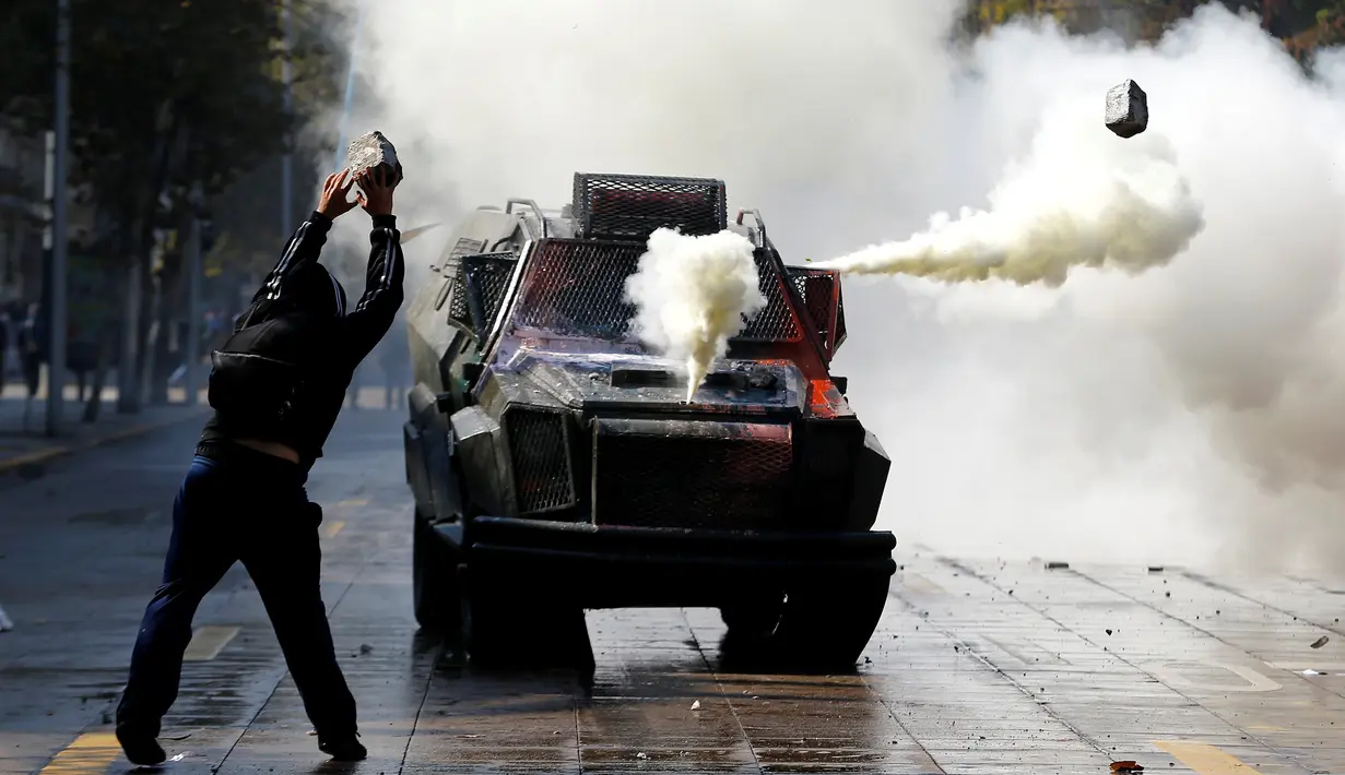 Pelajar melemparkan batu ke kendaraan anti huru-hara polisi di Santiago , Chile , 21 April 2016. Sejumlah pelajar nekat melempari polisi dengan batu dan bom rakitan. (REUTERS / Clemente Villavicencio)