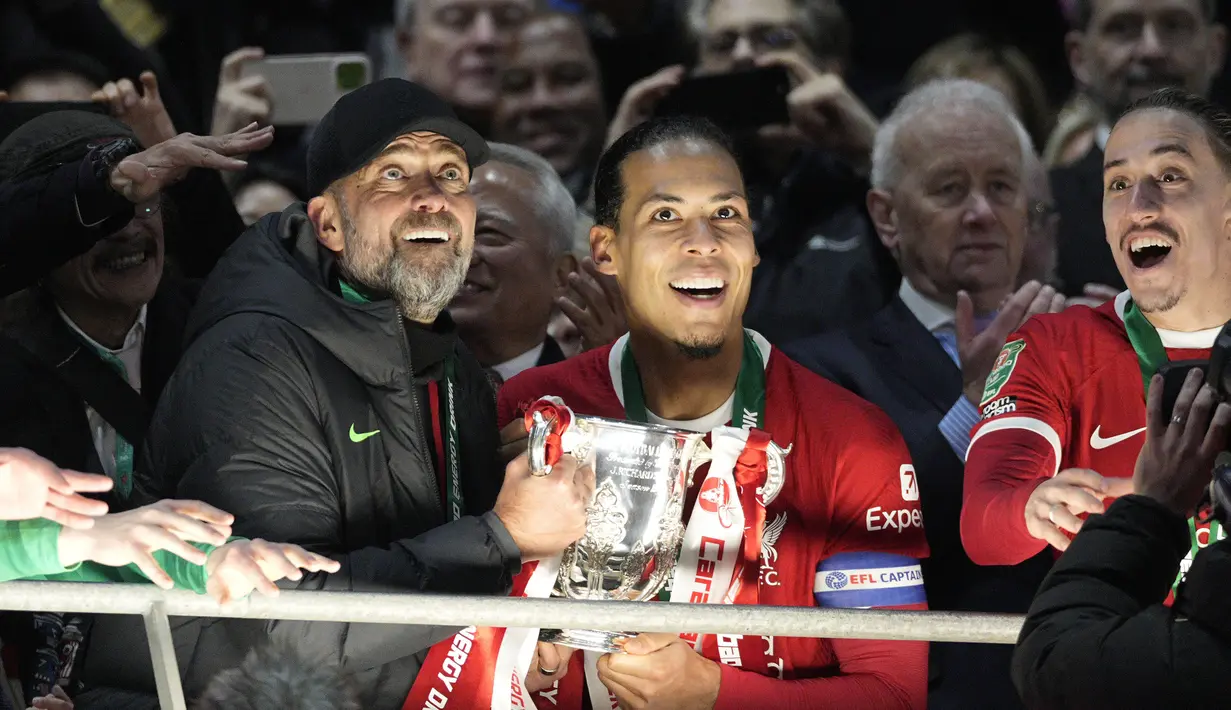 Pelatih Liverpool, Jurgen Klopp (tengah kiri) dan Virgil Van Dijk berisap mengangkat trofi Carabao Cup 2023/2024 di Stadion Wembley, Inggris, Minggu (25/02/2024). The Reds menang atas Chelsea dengan skor 1-0 melalui gol Virgil Van Dijk pada menit ke-118. (AP Photo/Dave Shopland)
