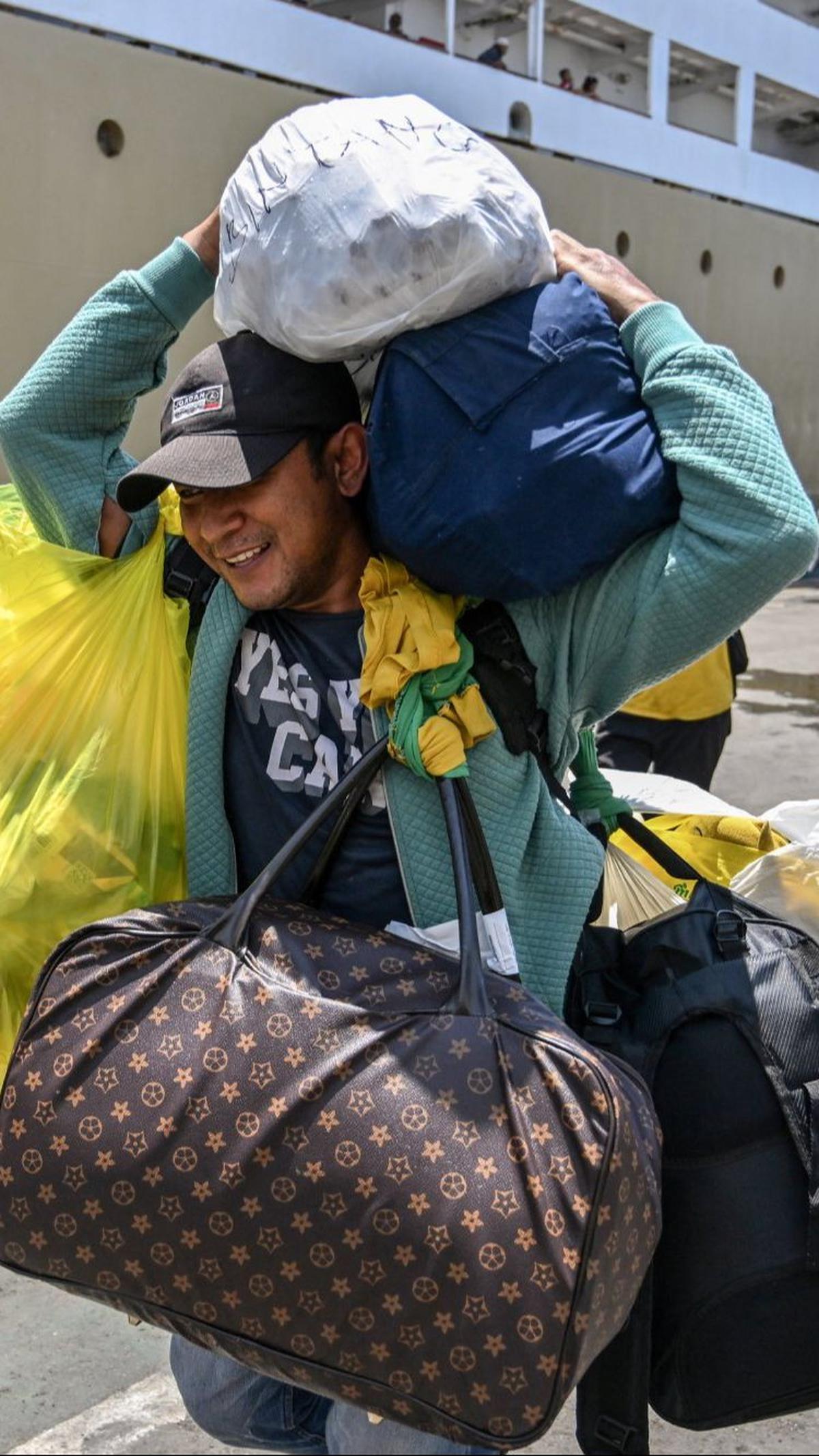 Penumpang membawa barang-barangnya saat tiba di Pelabuhan Tanjung Perak, Surabaya, Jawa Timur, Rabu (3/4/2024).&nbsp;Juni Kriswanto/AFP