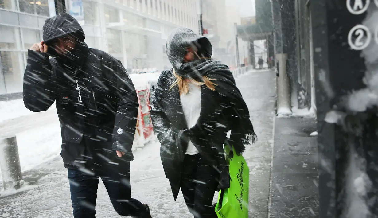 Pejalan kaki berjalan saat badai salju melanda Manhattan, New York City, AS (9/2). Badai salju akan terjadi di New York dan Philadelphia dengan kecepatan angin mencapai 48 kilometer per jam. (Spencer Platt / Getty Images / AFP)