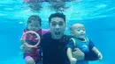 Tanpa memakai pelampung atau perlengkapan lainnya, Ricky Harun mengajak dua buah hatinya berfoto di dasar kolam renang. Terlihat ekspresi lucu dari papa ganteng yang satu ini dan dua anak mungil saat menahan napas ketika difoto. (Doc. Instagram)