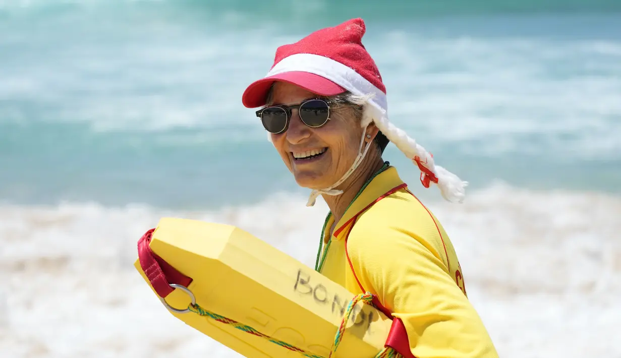 Seorang penyelamat mengenakan topi Santa sambil mengawasi orang-orang yang berkumpul di Pantai Bondi untuk merayakan Natal di Sydney, Sabtu