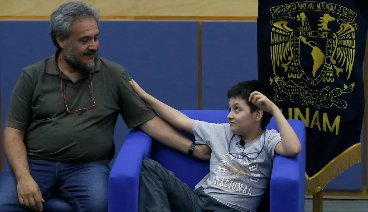 Carlos Santamaria Diaz (12) bersama sang ayah selama konferensi pers di Universitas Otonomi Nasional Meksiko di Mexico City, 3 Agustus 2018. Dengan sedikit gugup namun penuh semangat, ia bercita-cita menemukan obat untuk penyakit langka. (AP/Marco Ugarte)