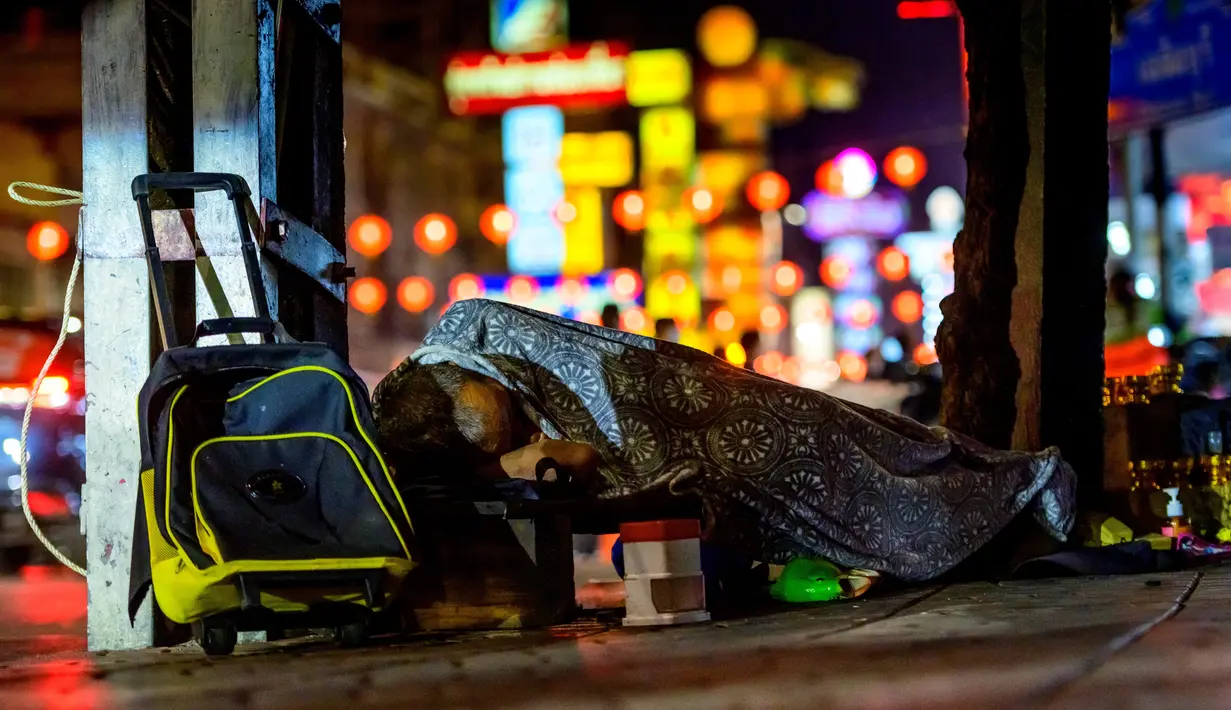 Seorang pria tunawisma tidur di jalan utama Chinatown Bangkok yang didekorasi untuk menyambut Tahun Baru Imlek (9/2/2021). Gubernur Asawin Kwanmuang mengumumkan bahwa pameran tahunan tidak akan dilaksanakan tahun Akibat pandemi COVID-19. (AFP/ Mladen Antonov)