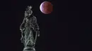 Bulan, dengan gerhana bulan sebagian atau parsial, terlihat di belakang Patung Kebebasan, di Capitol Hill di Washington, DC pada Jumat dini hari (19/11/2021).  (ANDREW CABALLERO-REYNOLDS / AFP)