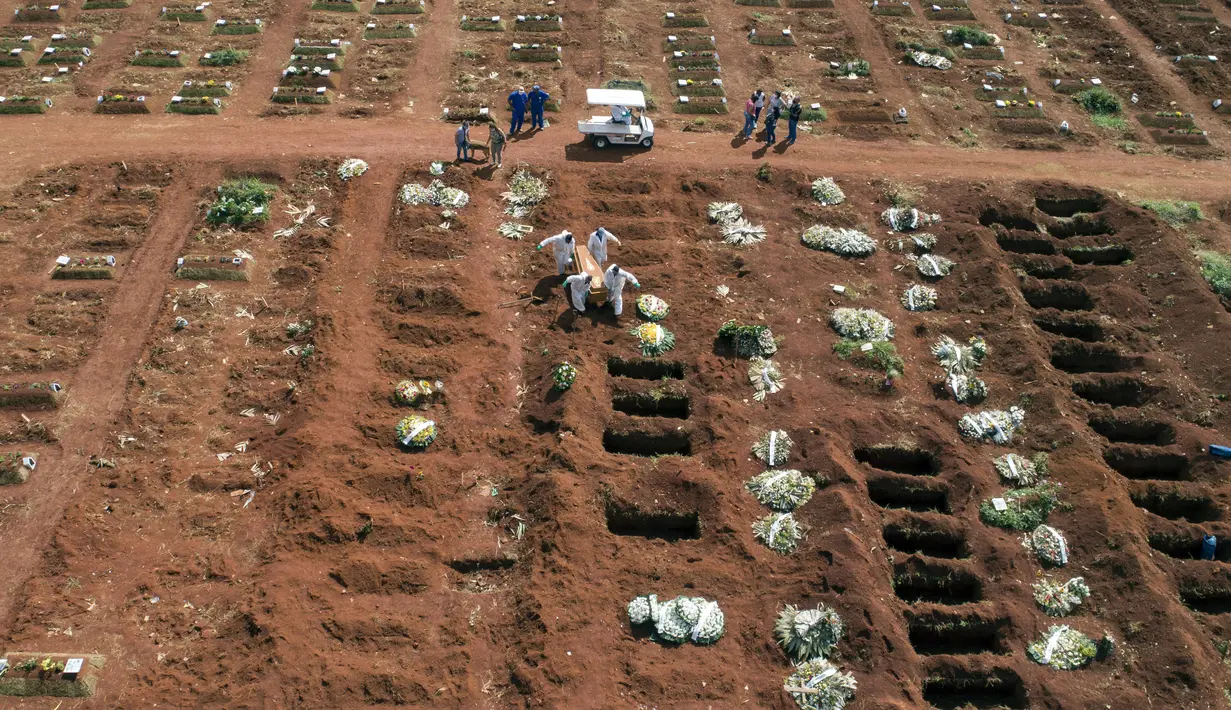 Petugas dengan pakaian pelindung membawa peti mati seseorang yang meninggal karena komplikasi COVID-19 ke dalam kuburan di pemakaman Vila Formosa di Sao Paulo, Brasil, Rabu (7/4/2021). Sao Paulo pada Rabu mulai menggali 600 kuburan tambahan setiap hari di pemakaman kotanya. (AP Photo/Andre Penner)