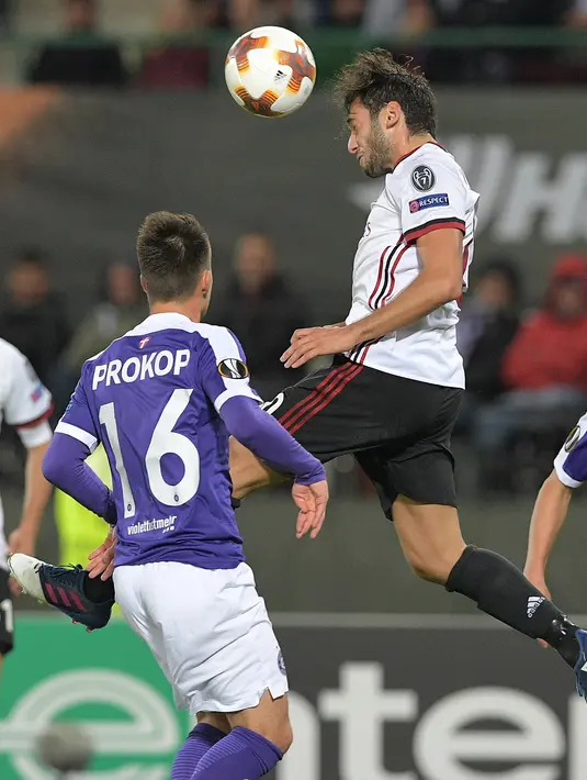 Gelandang AC Milan, Hakan Calhanoglu menyundul bola saat bertanding melawan  Austria Wien Felipe Pires saat bertanding pada Grup D Liga Europa di Ernst Happel Stadium, (14/9). Calhanoglu mencetak satu gol dipertandingan ini. (AFP Photo/Joe Klamar)