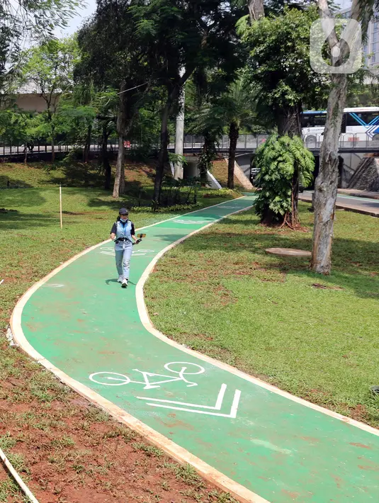 Seorang wanita berjalan melintasi jalur sepeda Taman Semanggi, Jakarta, Rabu (12/10/2022). Gubernur DKI Jakarta Anies Baswedan menyatakan pembangunan fasilitas pejalan kaki dan jalur sepeda itu bertujuan untuk memberikan ruang interaksi dan oase baru bagi warga Ibu Kota dan sekitarnya. (Liputan6.com/Herman Zakharia)
