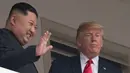 Pemimpin Korea Utara Kim Jong-un (kiri) melambaikan tangan saat tampil bersama Presiden AS Donald Trump di balkon Hotel Capella, Pulau Sentosa, Singapura, Selasa (12/6). Pertemuan keduanya membicarakan masalah denuklirisasi Korea Utara. (SAUL LOEB/AFP)