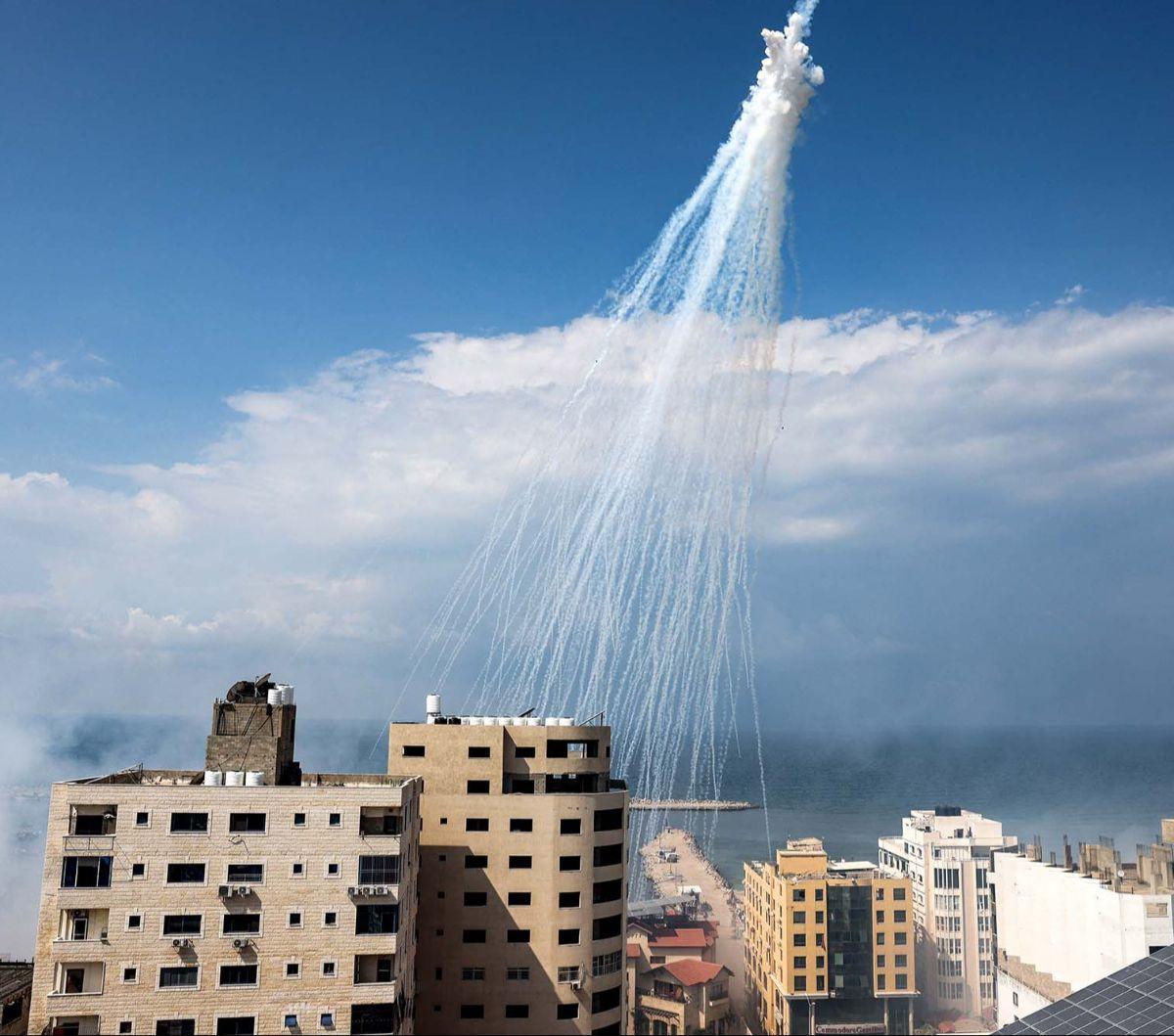 Seorang pewarta foto AFP, Mohammed Abed mengabadikan salah satu serangan Israel yang jatuh di dekat pelabuhan Jalur Gaza, Palestina, pada 11 Oktober 2023. Dalam serangan itu terlihat asap putih yang semburat dan jatuh di antara permukiman penduduk.
