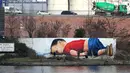 Grafiti raksasa buatan Justus Becker dan Oguz Sen bergambar Aylan Kurdi, bocah Suriah yang jasadnya ditemukan di pantai barat daya Turki pada September 2015, terpampang di sebuah tembok di sungai Main, Frankfurt, Jerman, 10 Maret 2016. (Daniel ROLAND/AFP)