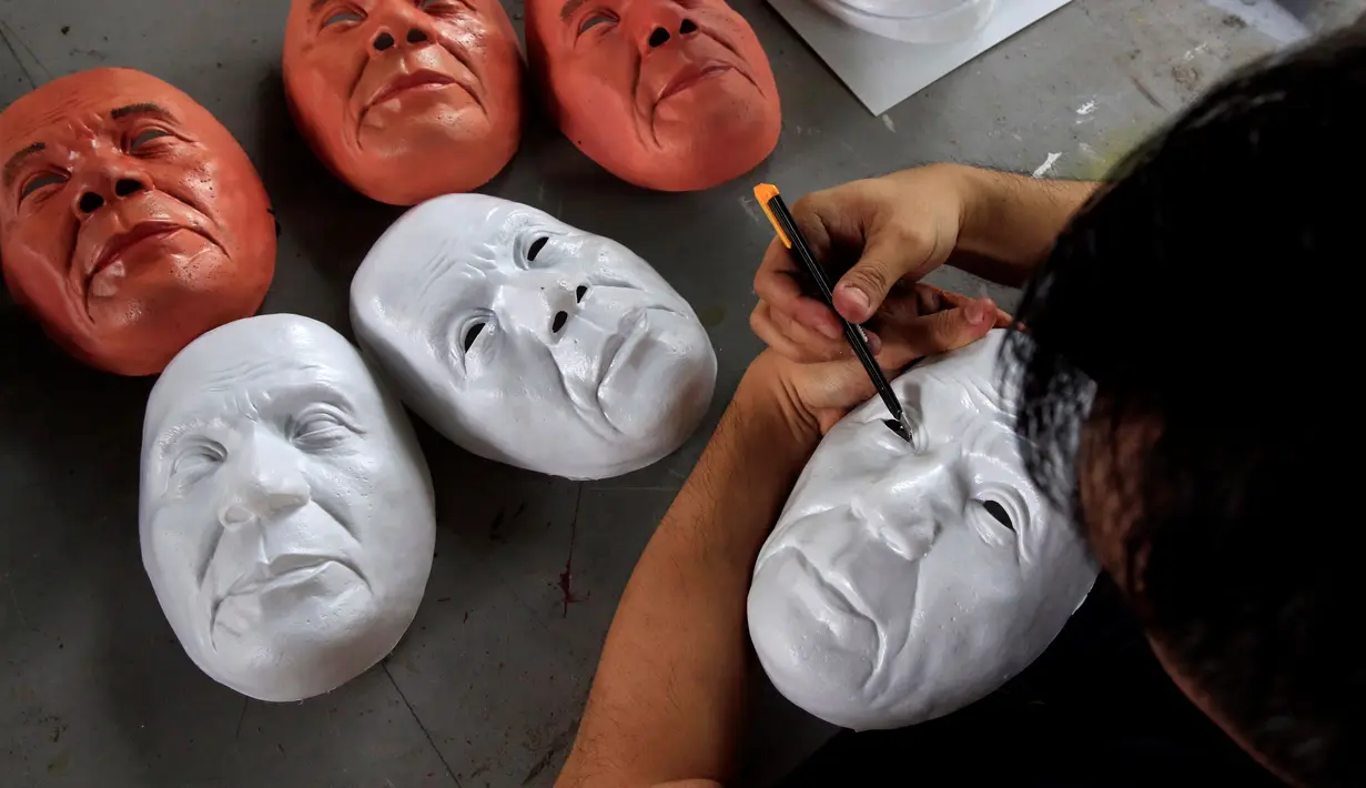 Mahasiswa seni rupa memotong topeng Presiden Rodrigo Duterte untuk perayaan Halloween di Universitas Filipina, Kota Quezon, Filipina (13/10). Topeng Duterte diyakini akan banyak diburu warga selama parayaan Halloween. (REUTERS/Romeo Ranoco)