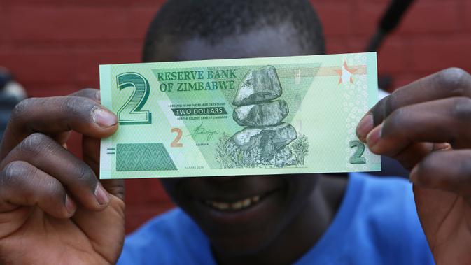 Seorang warga memegang salah satu uang kertas baru yang dikeluarkan Reserve Bank of Zimbabwe di Harare, 12 November 2019. Pemerintah Zimbabwe memperkenalkan kembali mata uang negaranya setelah hampir satu dekade terakhir menggunakan mata uang negara lain untuk bertransaksi. (AP/Tsvangirayi Mukwazhi)