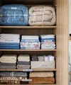 Cara menyimpan sprei dan selimut di lemari sempit agar tetap rapi dan hemat tempat. [AI Generated]