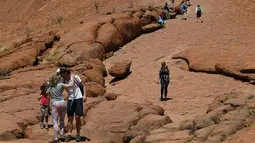 Wisatawan mendaki Uluru yang juga dikenal sebagai Batu Ayers di Taman Nasional Uluru-Kata Tjuta, utara Australia, Jumat (25/10/2019). Kawasan wisata bukit batu Uluru dipenuhi pengunjung, lantaran hari ini merupakan hari terakhir sebelum larangan pendakian diberlakukan. (SAEED KHAN / AFP)