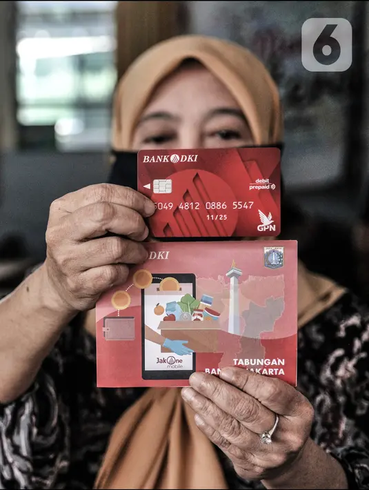 Warga menunjukkan kartu ATM dan buku rekening Bank DKI yang berisi dana BST di SMPN 3, Jakarta, Selasa (26/1/2021). Pencairan BST di Provinsi DKI Jakarta dilakukan secara bertahap mulai Januari-April 2021. (merdeka.com/Iqbal S. Nugroho)