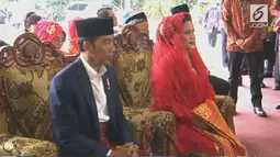 Presiden Joko Widodo dan Ibu Negara Iriana mendengarkan sambutan saat mengikuti  prosesi penyambutan keluarga mempelai wanita secara adat di Bukit Hijau Regency Taman Setia Budi (BHR Tasbi), Medan, Sabtu (25/11). (Liputan6.com/vidio)