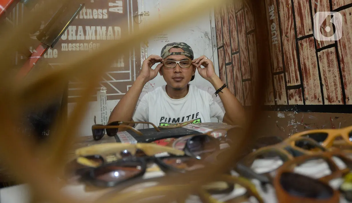 Perajin Yuyud Wahyudi (39) menyelesaikan pembuatan frame kacamata dari limbah kayu bekas di Pondok Benda, Pamulang, Tangsel, Kamis (8/10/2019). Sebelum pandemi, Yuyud menerima banyak pesanan seperti dari Italia, Norwegia, Prancis dan Jerman, namun kini turun hingga 75 persen. (merdeka.com/Dwi Narwok