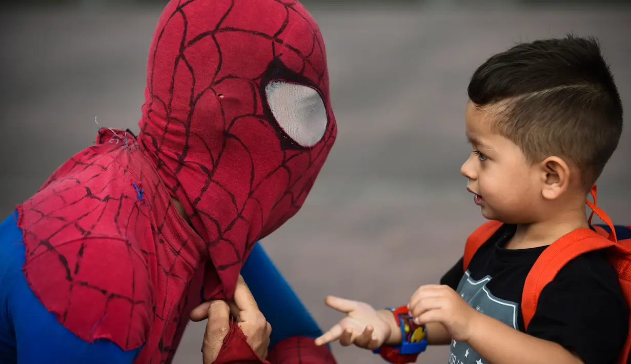 Jahn Fredy Duque berbincang dengan seorang bocah di jalanan Bogota, Kolombia, Senin (24/4). Duque mencari nafkah dengan melakukan atraksi layaknya Spiderman. (AFP Photo/RAUL ARBOLEDA)