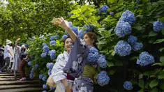 Pengunjung melepas masker untuk berfoto saat bunga hydrangea bermekaran penuh di Meigetsu-in kuil Buddha di Kamakura, Tokyo, Jumat (11/6/2021).  (AP Photo/Kiichiro Sato)