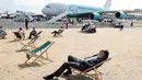 Pengunjung beristirahat di dek kursi dekat pesawat penumpang Airbus A380 di Farnborough Airshow, London, Inggris, Kamis (19/7). (Adrian DENNIS/AFP)
