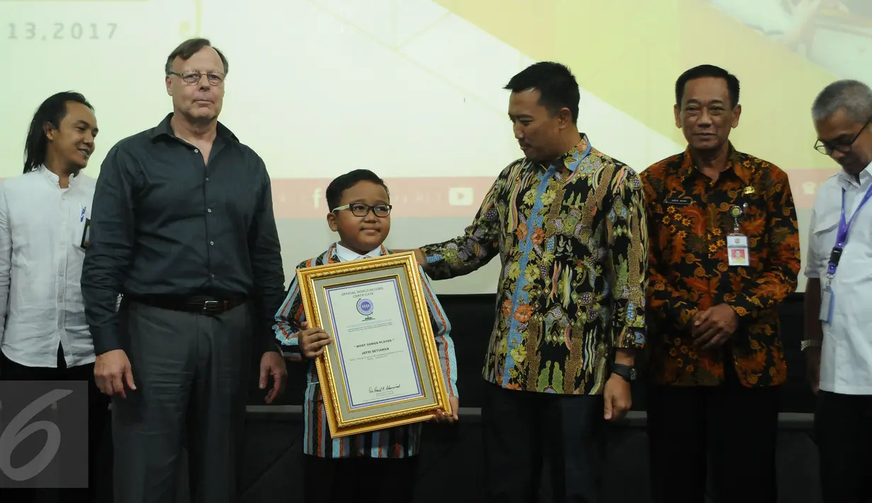 Jefri Setiawan (tengah) usai menerima penghargaan dari Official World Record di Auditorium Kemenpora, Jakarta, Kamis (14/11). Jefri mencatat rekor dunia baru memainkan 60 lagu menggunakan keyboard dengan mata tertutup. (Liputan6.com/Helmi Fithriansyah)