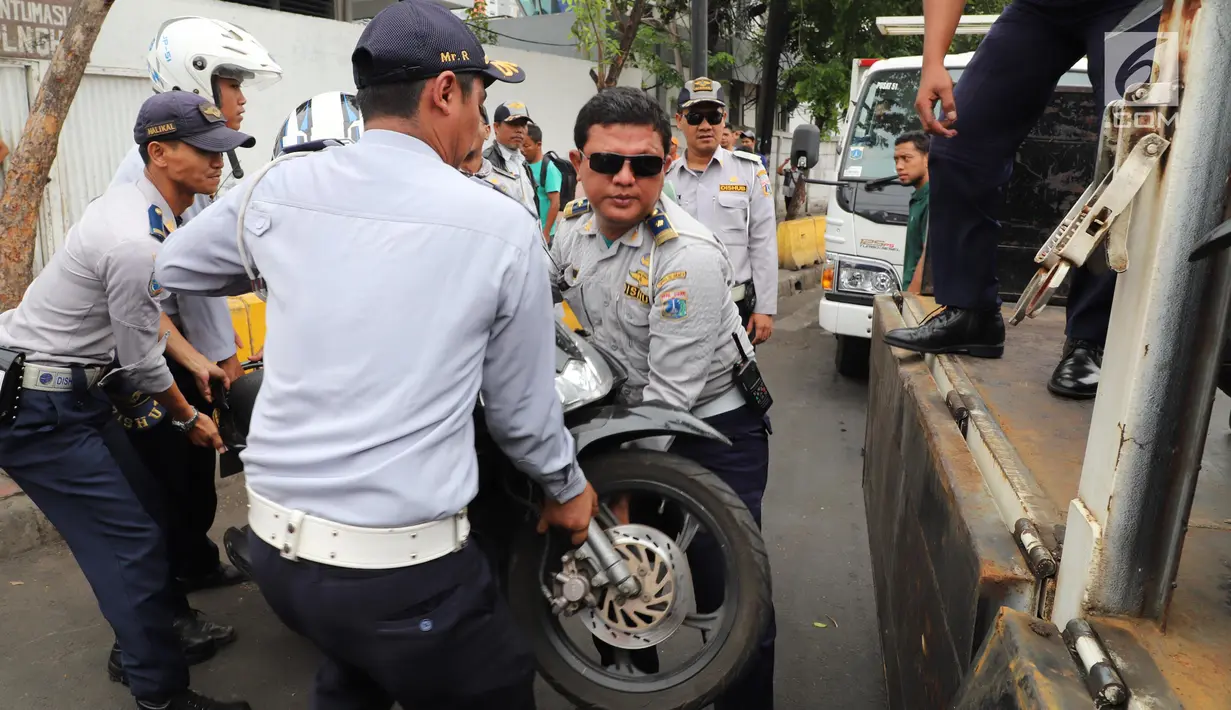 Petugas Dishub DKI mengangkut sepeda motor saat operasi penertiban di Pasar Tanah Abang, Jakarta, Senin (21/5). Banyak preman yang memanfaatkan momen meningkatnya pengunjung pasar Tanah Abang dengan membuka area parkir liar. (Liputan6.com/Arya Manggala)