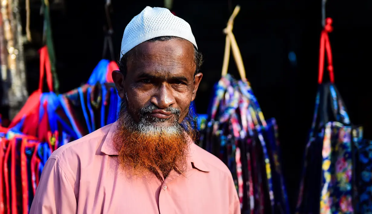 Dalam gambar yang diambil pada 24 Desember 2018, penjual sayur bernama Siddikur Rahman berpose dengan janggut oranye di Dhaka. Belakangan ini, pria-pria Muslim Bangladesh keranjingan berpenampilan dengan janggut warna-warna terang seperti merah hingga oranye. (MUNIR UZ ZAMAN / AFP)