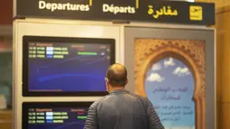 Pelancong memeriksa jadwal penerbangan yang dibatalkan dan berangkat di terminal di bandara Rabat, Senin (29/11/2021). Maroko menangguhkan semua penerbangan internasional mulai Senin tengah malam selama dua minggu karena kekhawatiran pada varian baru Covid-19 Omicron. (AP Photo/Mosa'ab Elshamy)