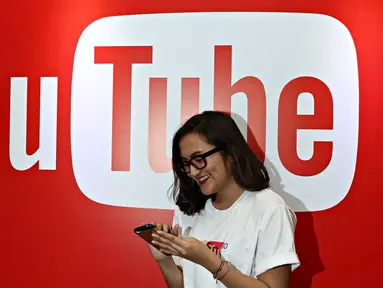 Seorang wanita melintas di depan backdrop YouTube dalam acara yang diselenggarakan YouTube, Jakarta, Selasa (20/10/2015). Menurut Google Indonesia jumlah video yang diunggah pengguna YouTube Indonesia meningkat hingga 600% (Liputan6.com/Immanuel Anton)