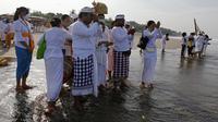 Orang-orang mencelupkan kaki mereka di laut selama ritual Melasti di Bali, Senin (28/2/2022). Ritual yang dilakukan menjelang Hari Raya Nyepi umat Hindu ini diadakan untuk menyucikan alam semesta dari pengaruh buruk, perbuatan dan pikiran buruk. (AP Photo/Firdia Lisnawati)