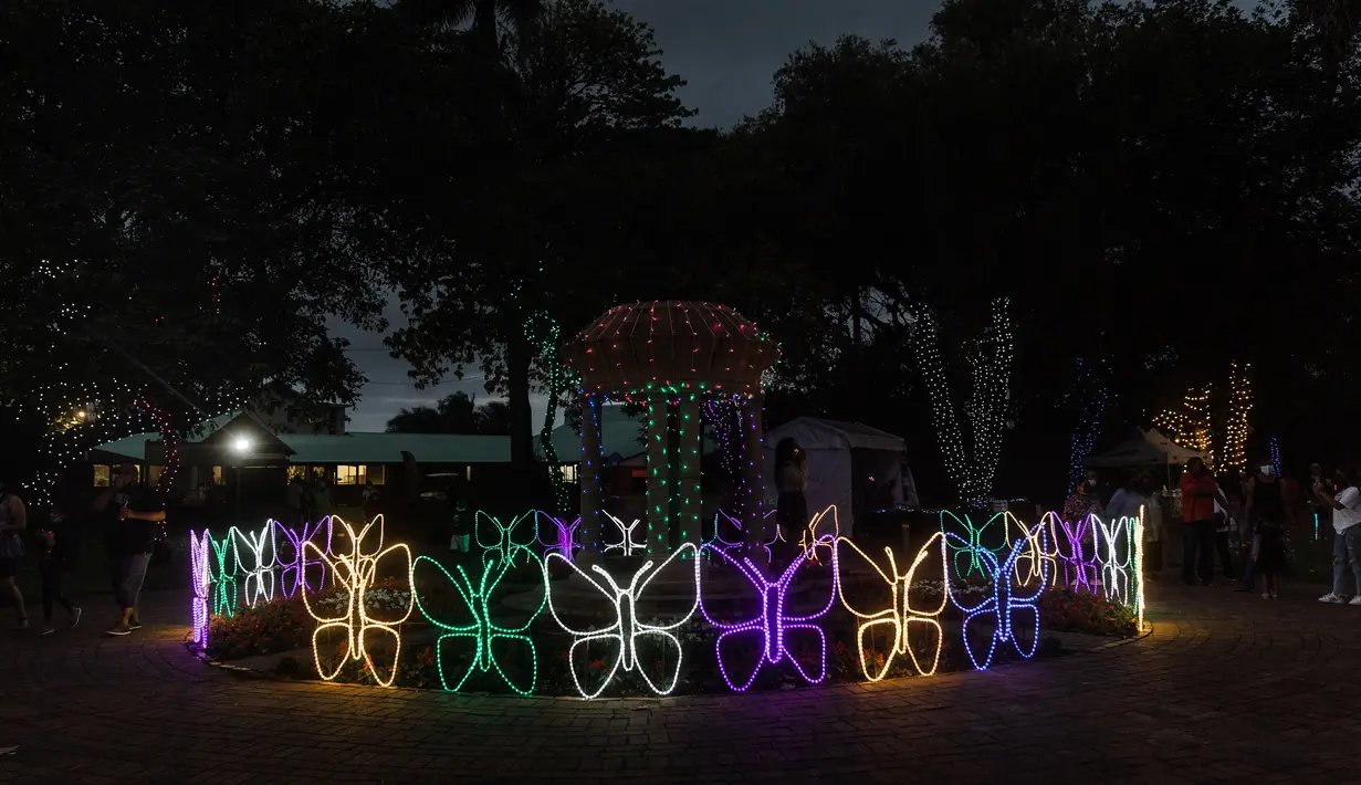 Orang-orang mengunjungi "Trail of Lights" Kebun Raya Durban menjelang Natal di Durban, Afrika Selatan (14/12/2021). Tahun ini taman akan kembali dihiasi dengan jutaan lampu dengan tampilan pencahayaan baru. (AFP/Rajesh Jayantilal)
