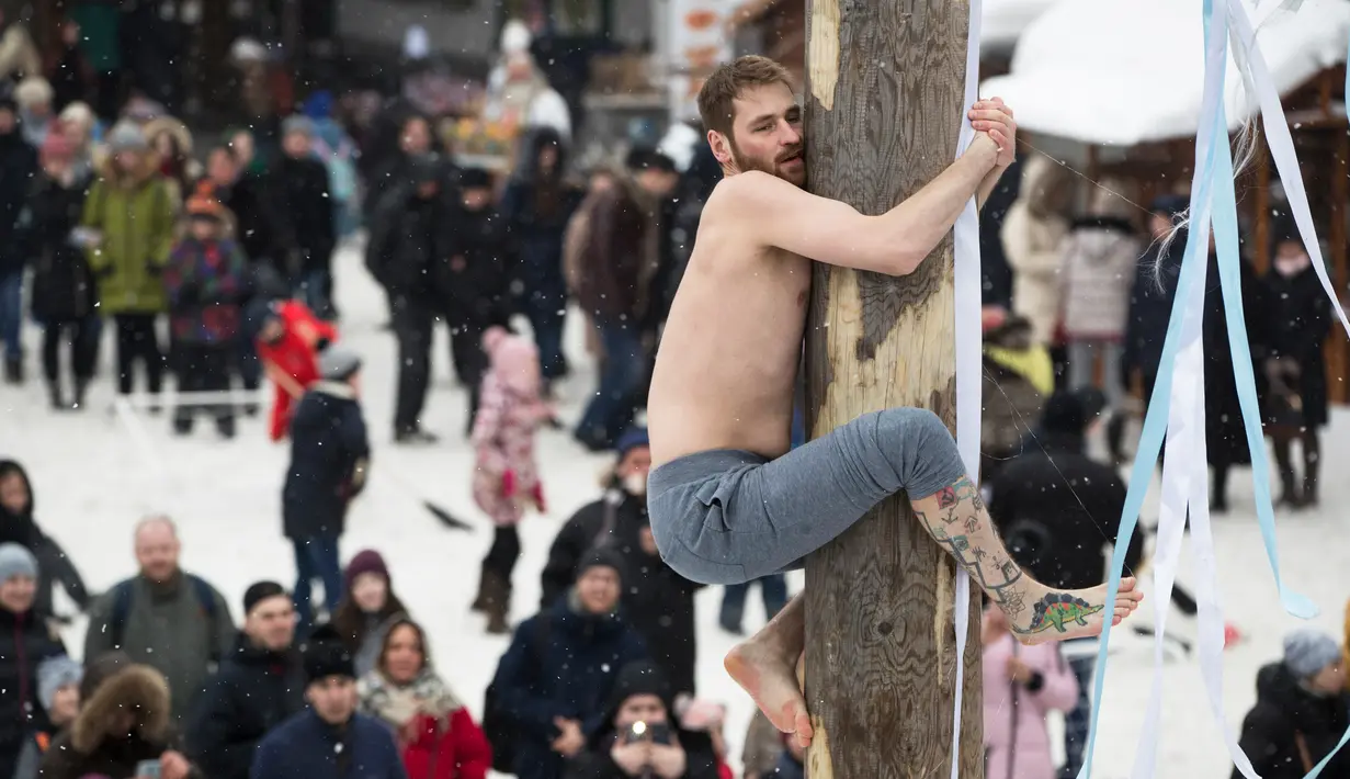 Seorang pria berusaha memanjat di sebuah tiang saat perayaan liburan Maslenitsa (Shrovetide) di Moskow, Rusia (18/2). Liburan ini menandai berakhirnya musim dingin yang dirayakan sejak masa pagan. (AP Photo / Pavel Golovkin)