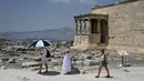 <p>Turis menggunakan payung untuk melindungi diri dari sinar matahari saat mengunjungi Acropolis di Athena, Yunani, Minggu (24/7/2022). Negara ini berada dalam cengkeraman gelombang panas yang dimulai pada 23 Juli dan akan berlangsung beberapa hari. Suhu diperkirakan akan mencapai 42 derajat Celcius (107 derajat Fahrenheit) di beberapa daerah. (Louisa GOULIAMAKI / AFP)</p>